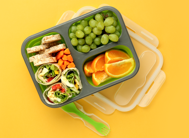 healthy lunch box with fruit and vegetables on a yellow background